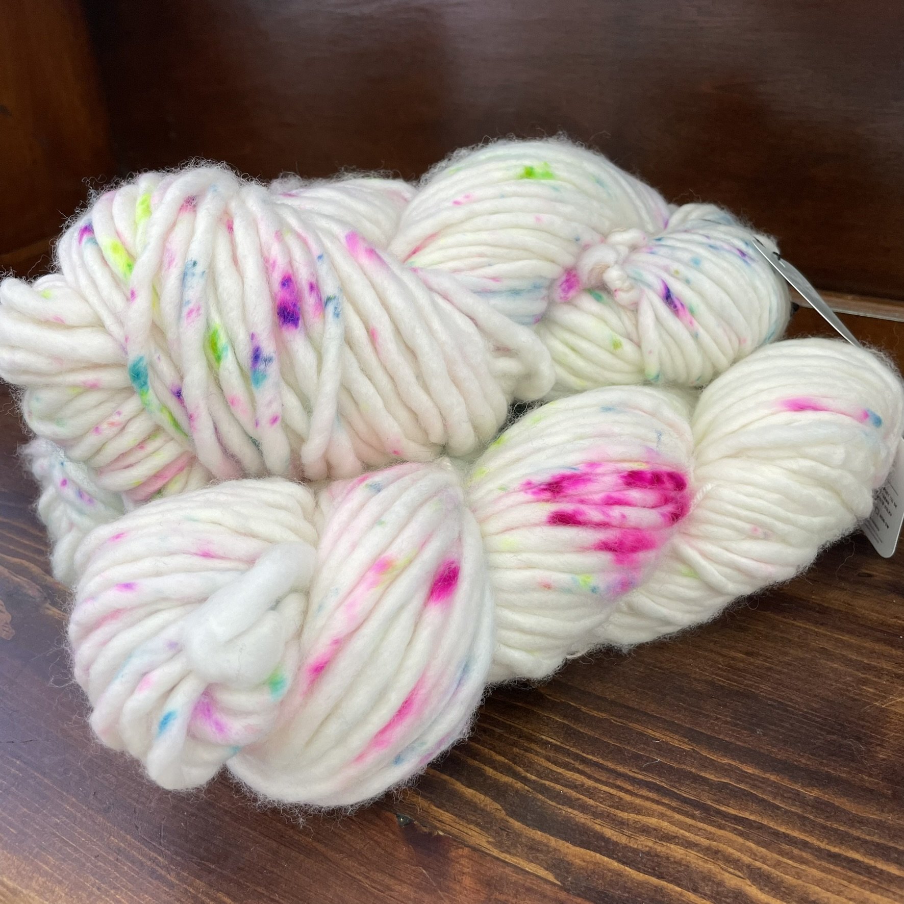 Side-angle view of Honey & Clover Super Bulky yarn in Confetti, showing colorful specks on white wool.
