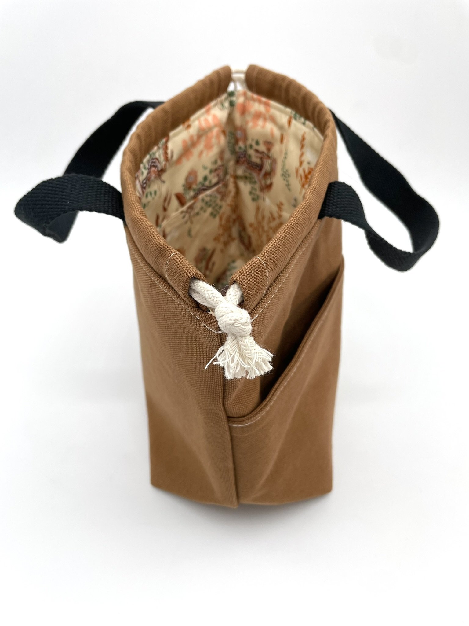 Top-side view of the small brown Puff Stitch project bag showing the opening and handles.