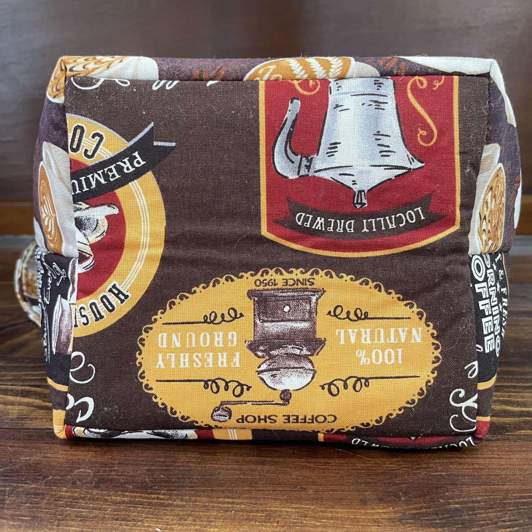 Bottom view of a large coffee-themed project bag, highlighting the fabric’s coffee grinder and espresso cup motifs.