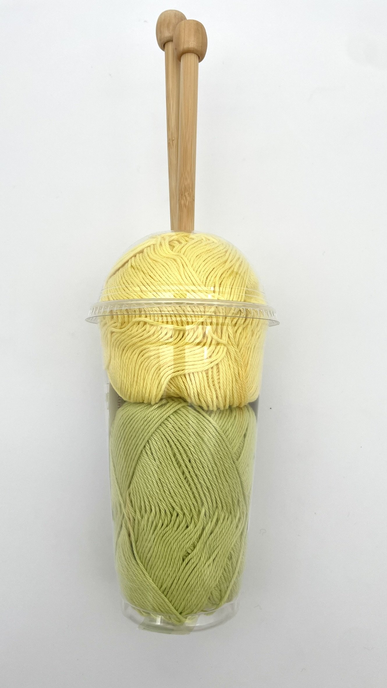 DIY Smoothie Scarf kit in yellow and green with bamboo knitting needles back view.