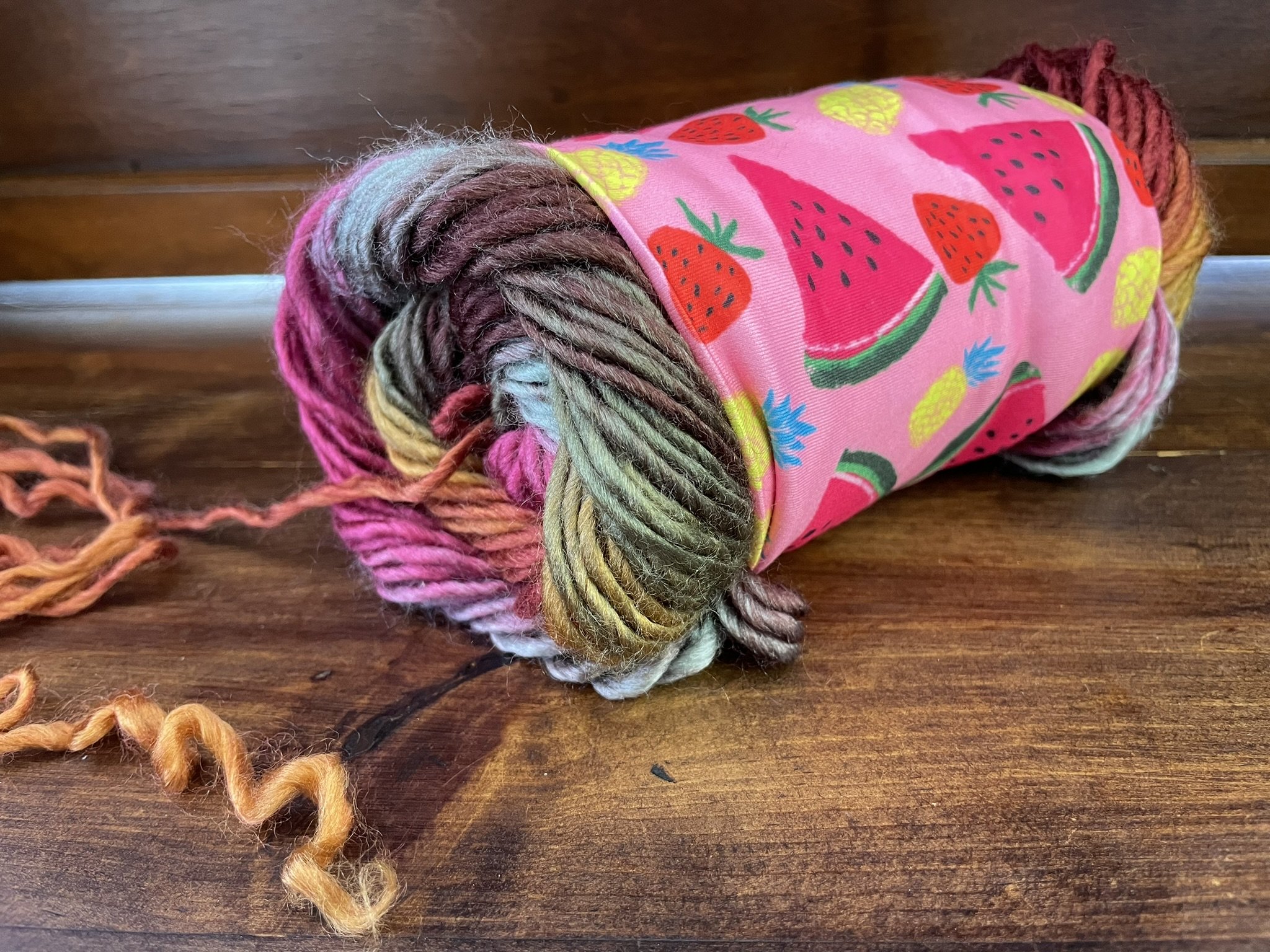 Fox & Pine yarn sweater in watermelon print wrapped around a skein of yarn, keeping it organized during use.