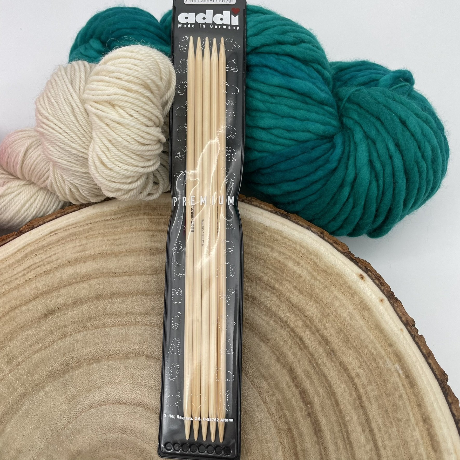 Addi 8-inch bamboo double-pointed needles with premium packaging and colorful yarn background.
