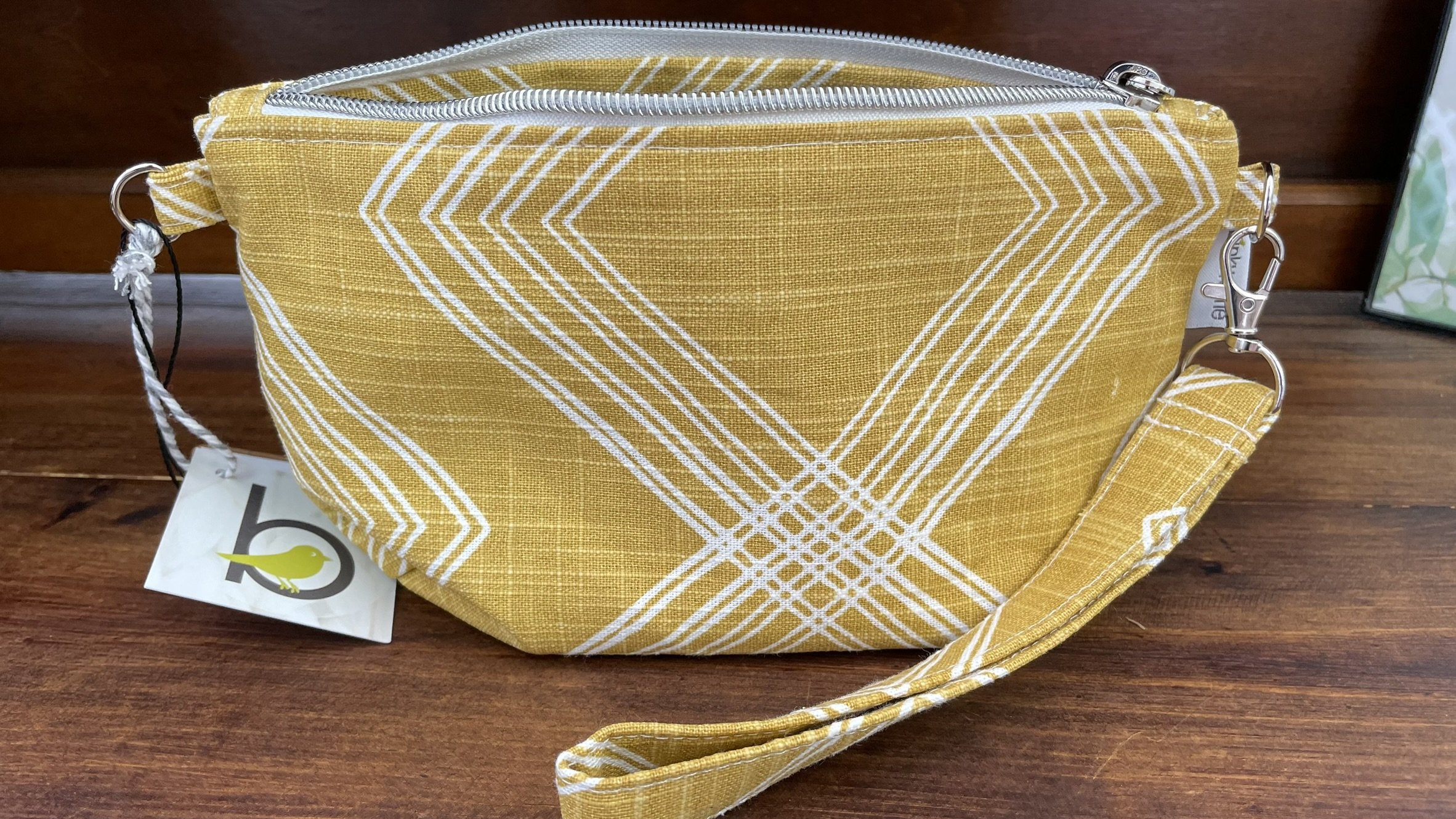 Bright yellow zippered accessories pouch with a geometric design, made from durable fabric with a wrist strap for convenience.