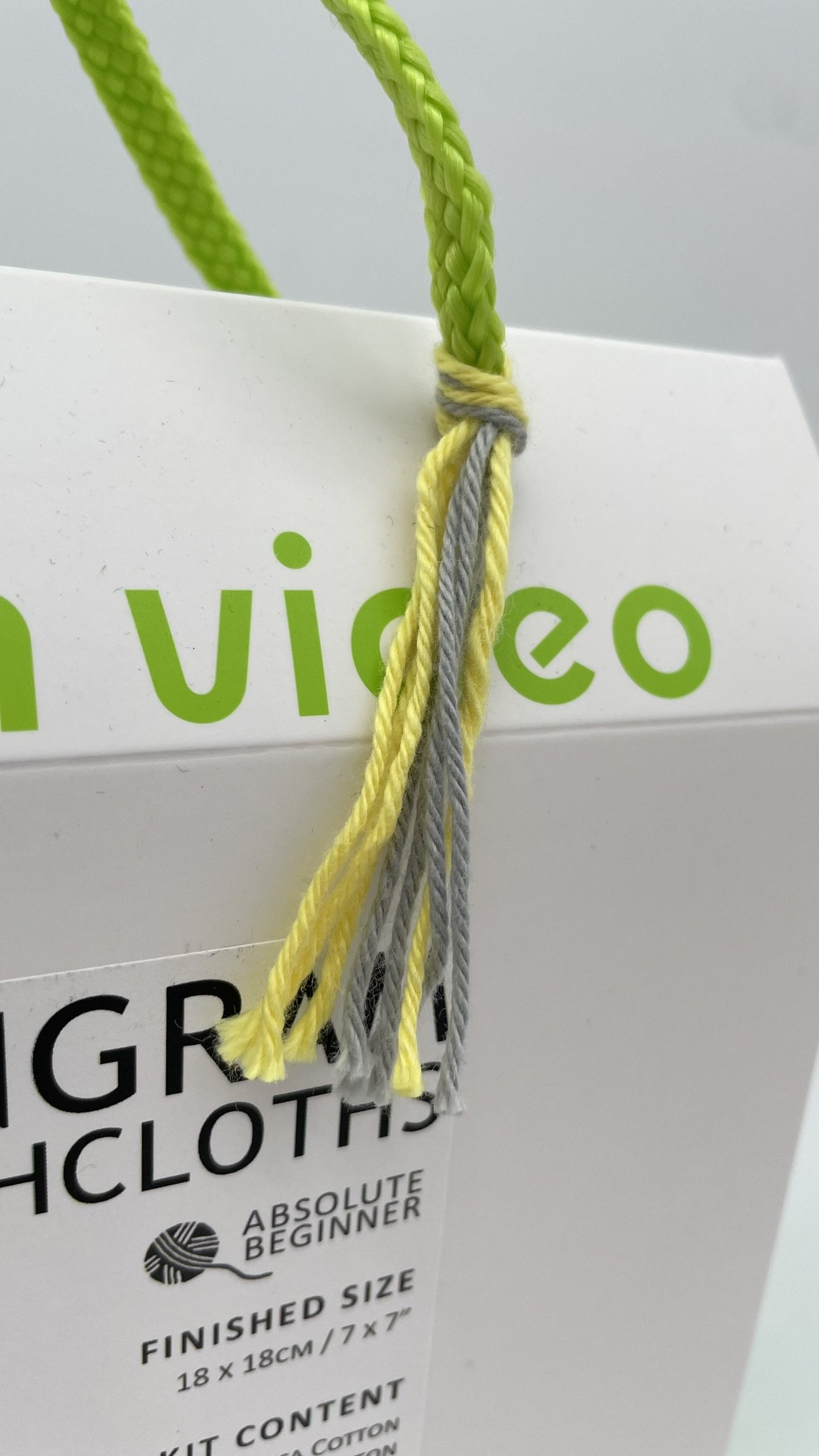 DIY Knitting Kit for Tangram Dishcloths by Knitca featuring gray and yellow yarn with bamboo needles, beginner-level project.