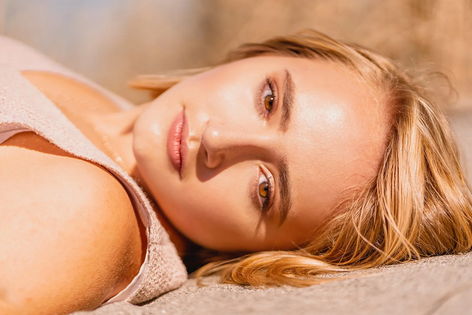 Close-up of a person lying down with sunlit face and light hair.