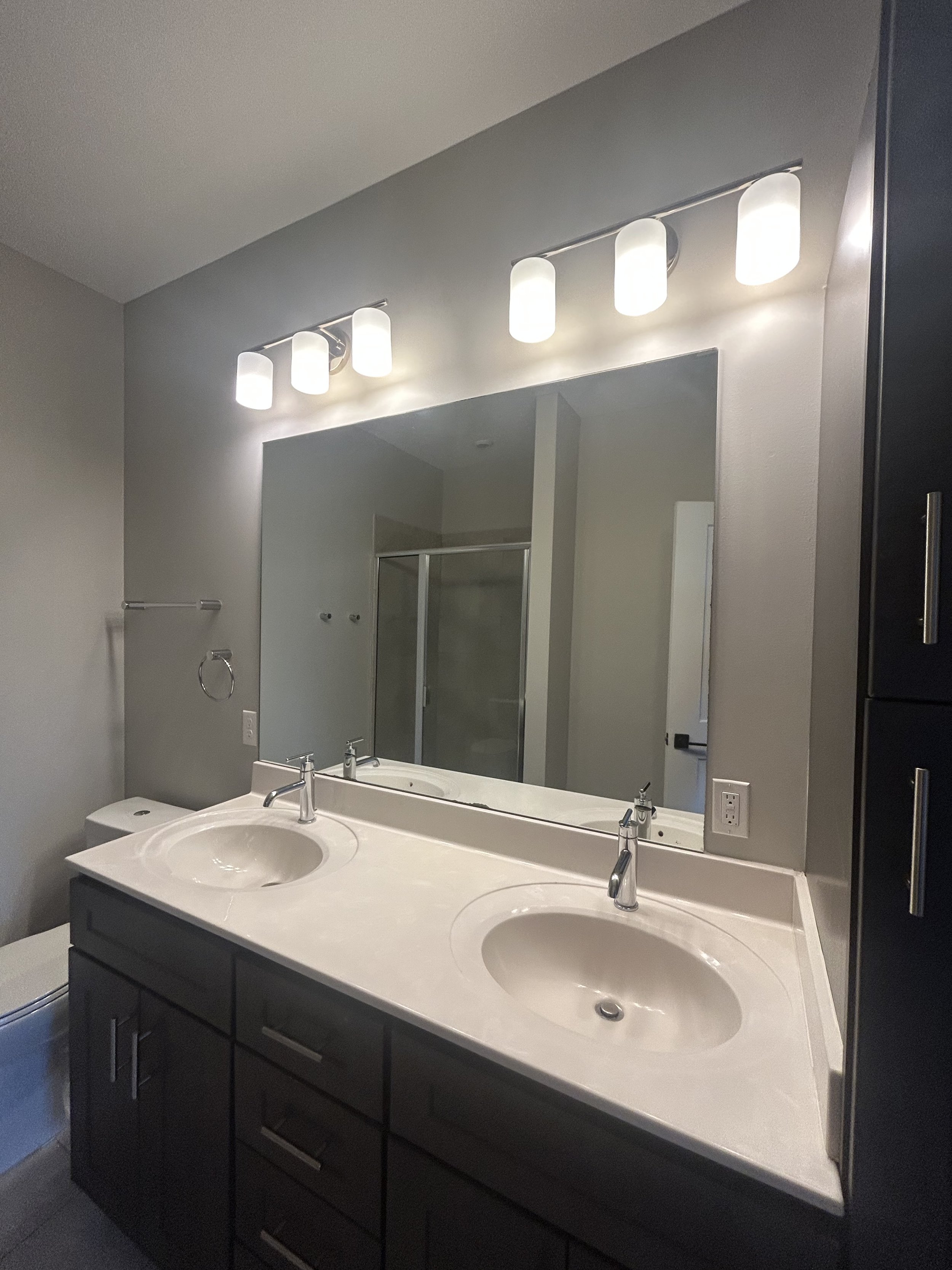 Bathroom with double sinks, large mirror, and four-light vanity fixture above the mirror.