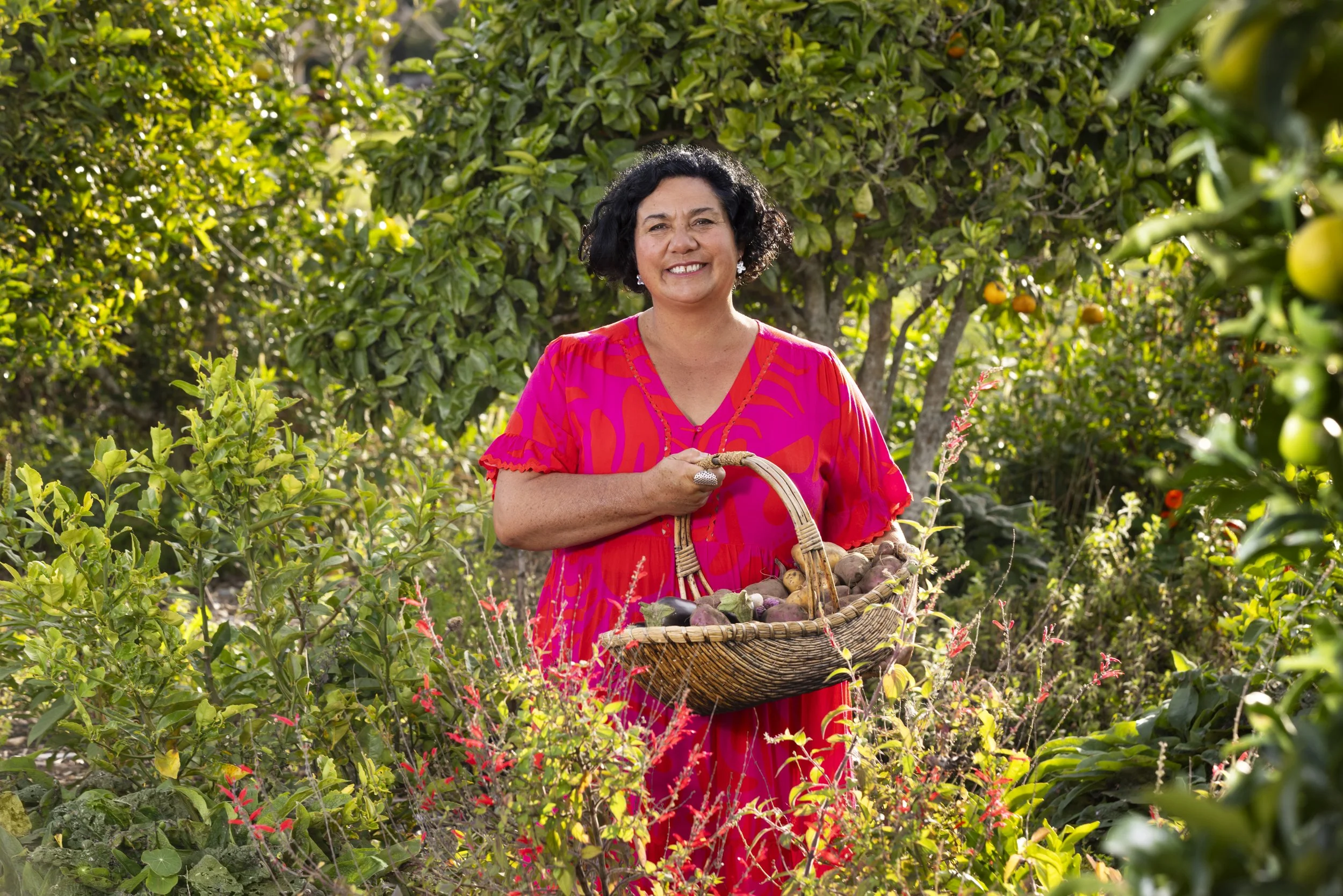 Woman standing in an abundant garden holding a basket