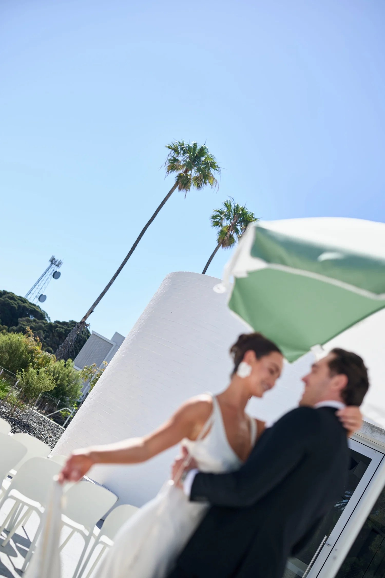 A couple dancing beside a green and white umbrella in the sun