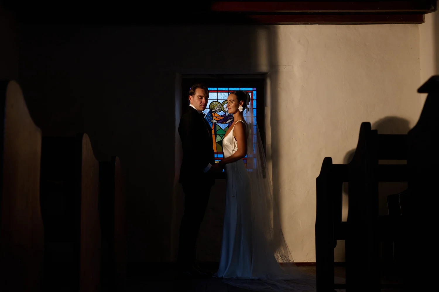 A couple framed by a stained glass window in soft light