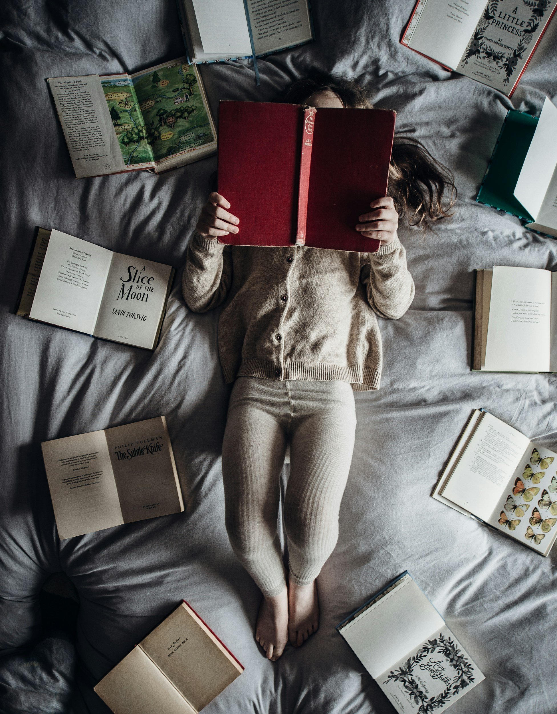 Reader in bed surrounded by books