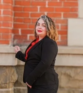 A close-up of a pink gerbera daisy flower on a green stem against a light blue background.