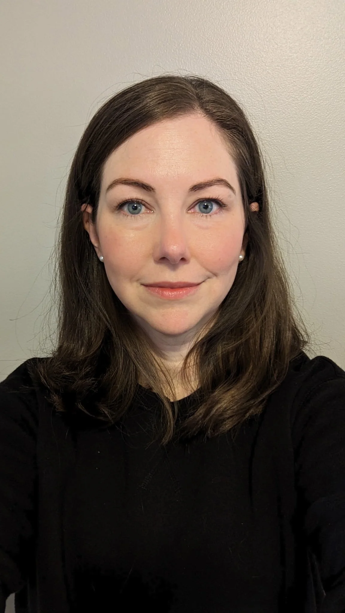 A close-up of a single pink and white daisy flower with a green stem set against a light blue background.