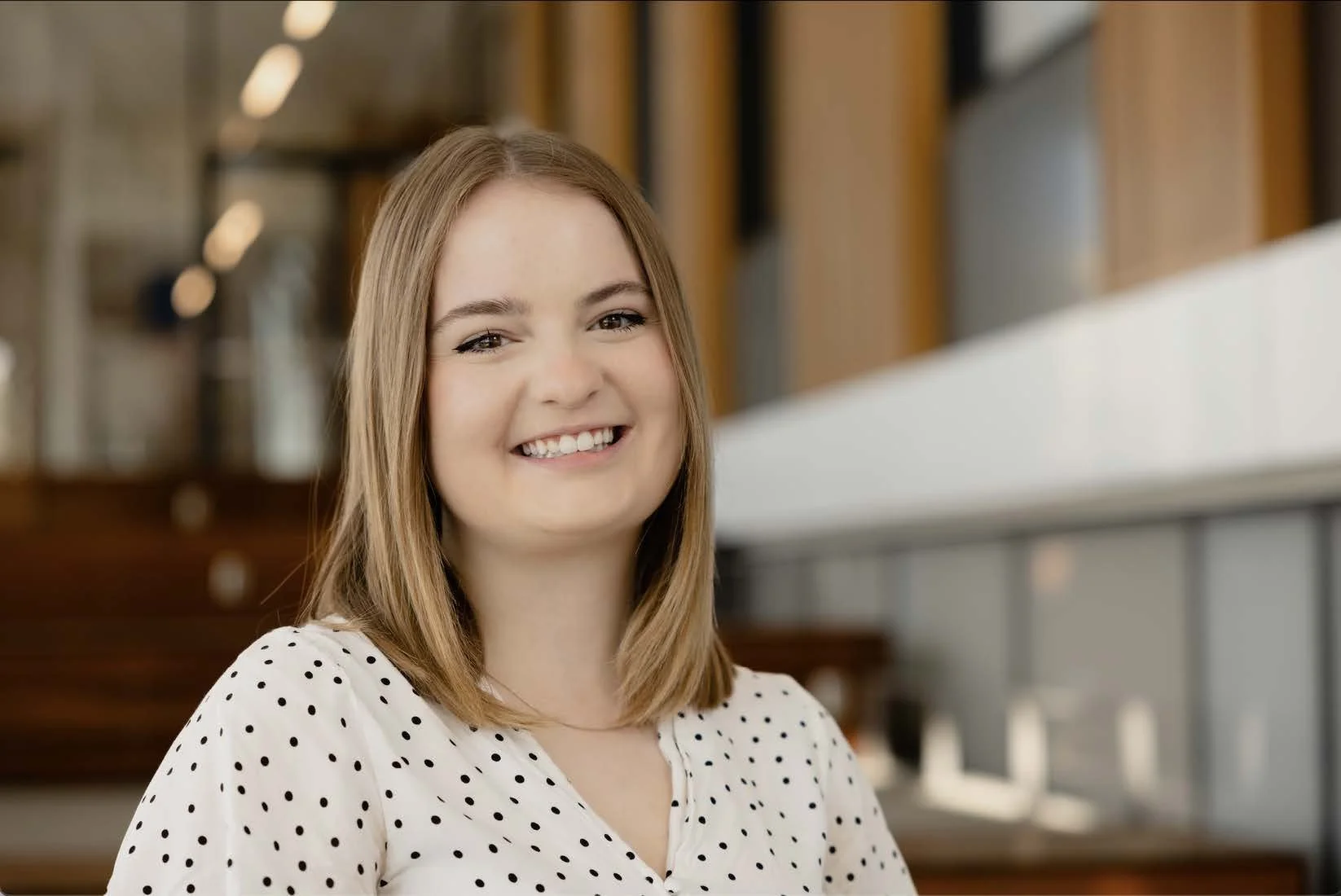 A close-up of a soft pink gerbera daisy flower with a green stem against a light blue background.