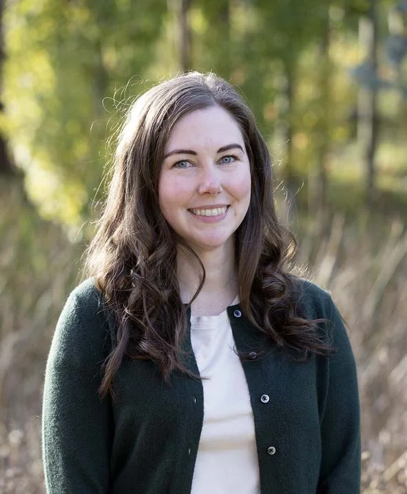 A close-up of a single pink and white daisy flower with a green stem set against a light blue background.