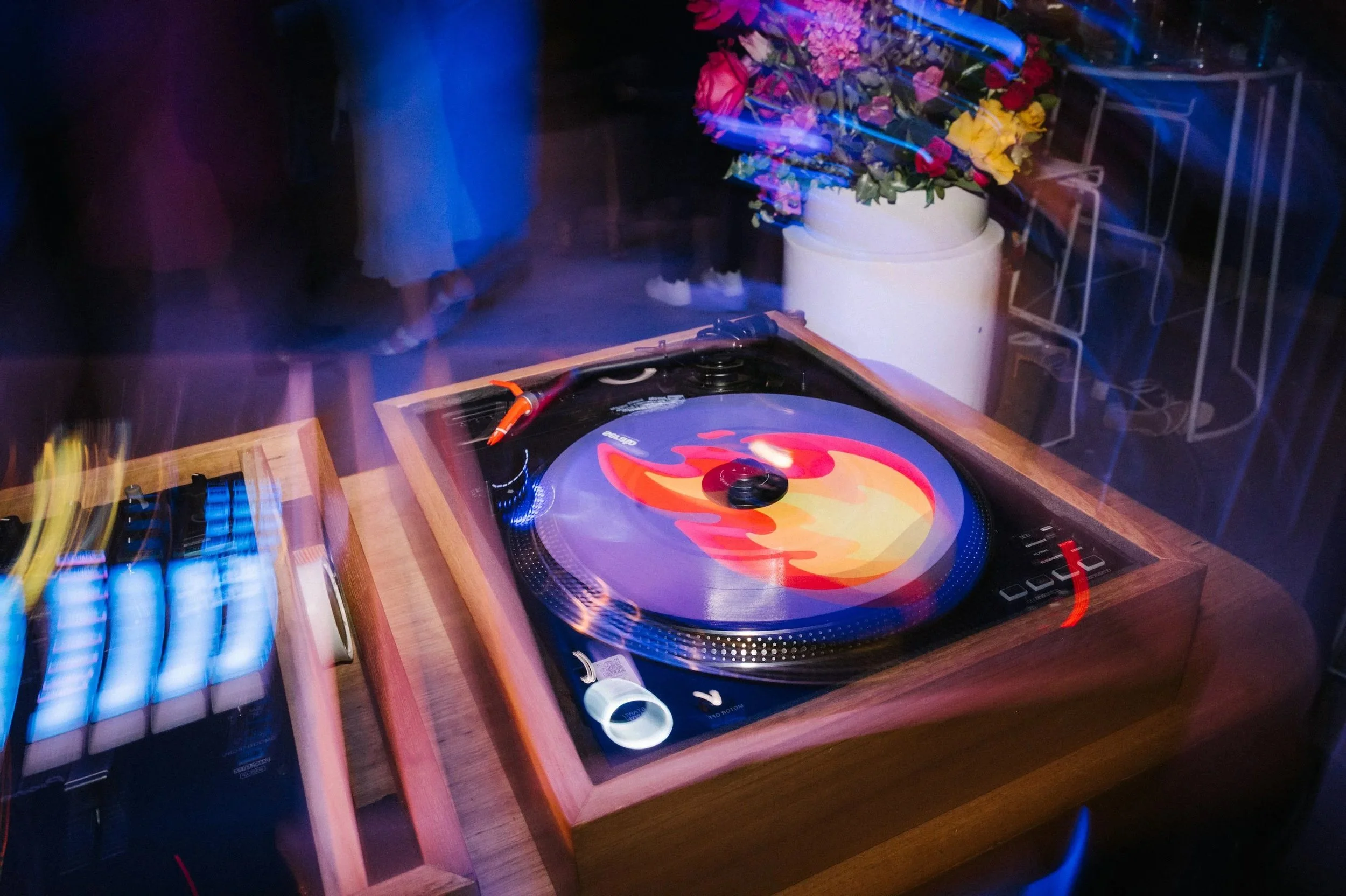 Two DJs standing behind vinyl turntables and putting their hands up in the air