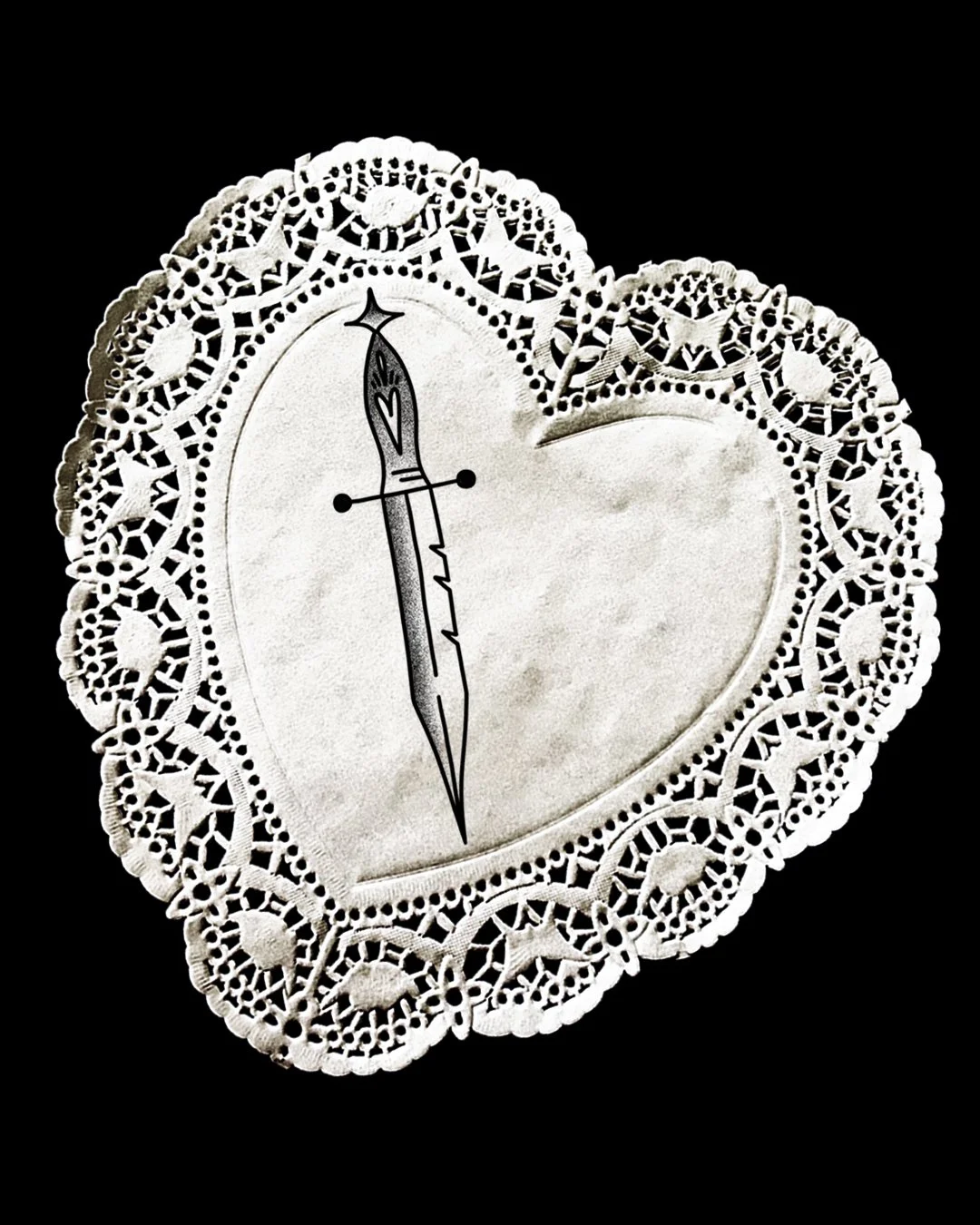 A decorative lace heart-shaped tray with a tattoo-style dagger design in the center.