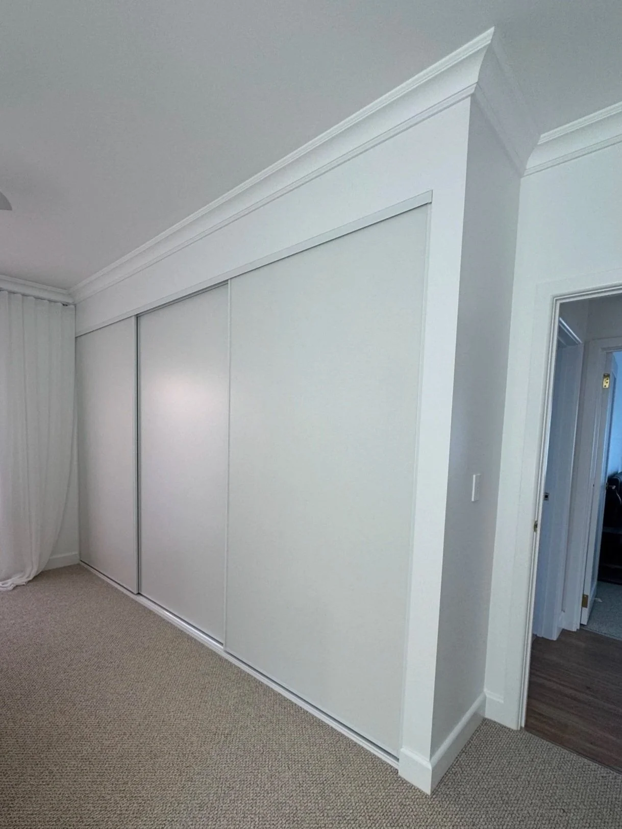 White sliding closet doors in a room with beige carpet and white walls.