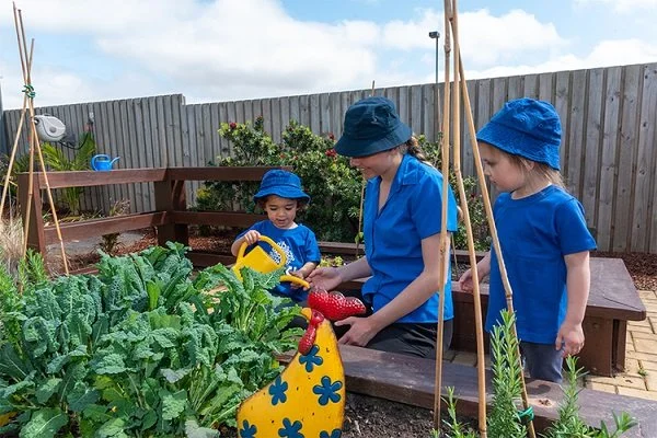Educator and children water the plants in the garden at Highfields Central Early Learning Centre