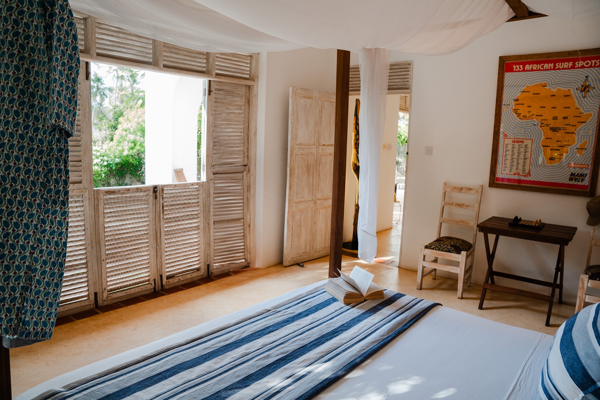 Downstairs bedroom featuring x2 king-size beds, and doors opening onto the pool area.