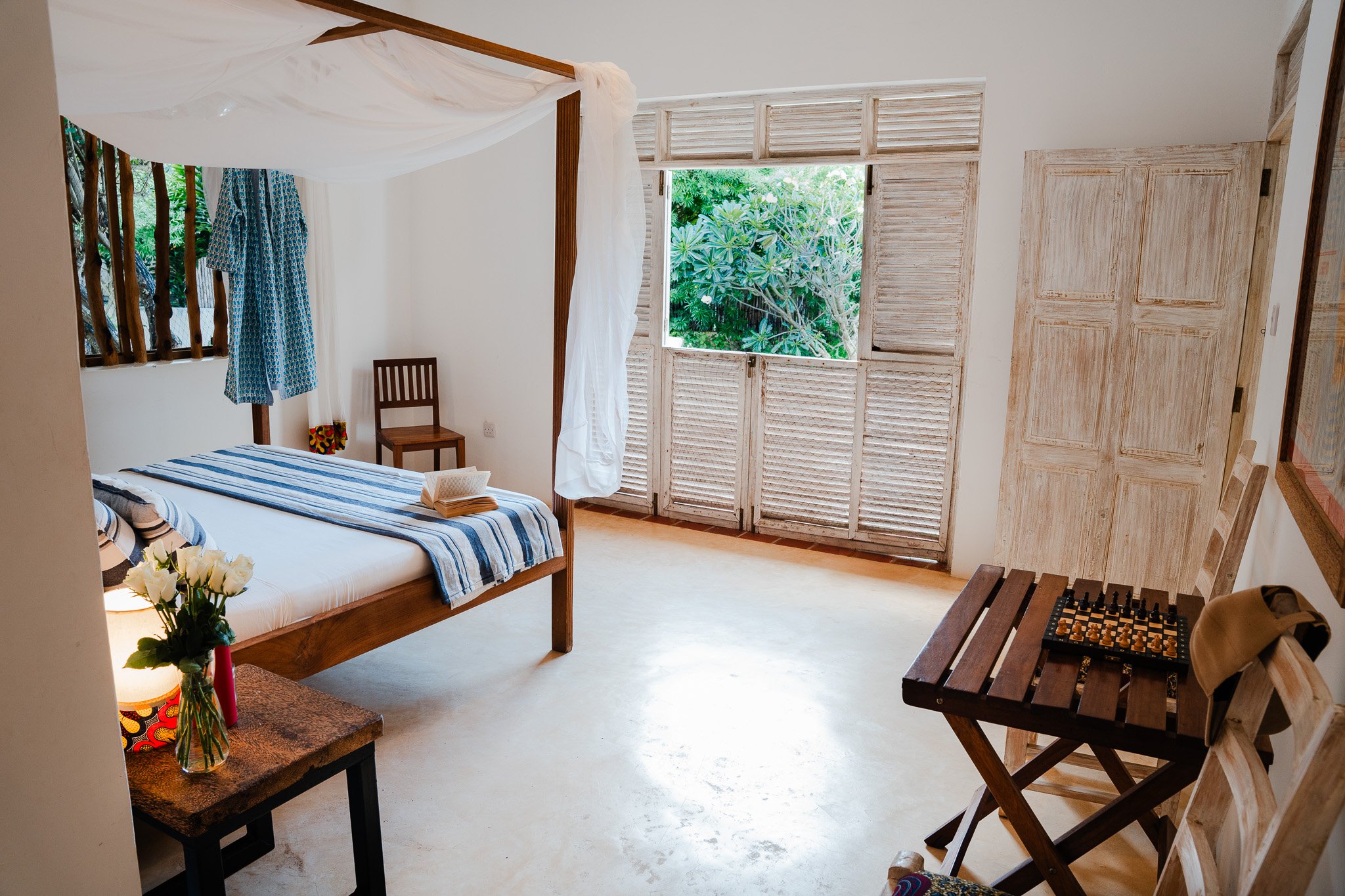 Downstairs bedroom featuring x2 king-size beds, and doors opening onto the pool area.