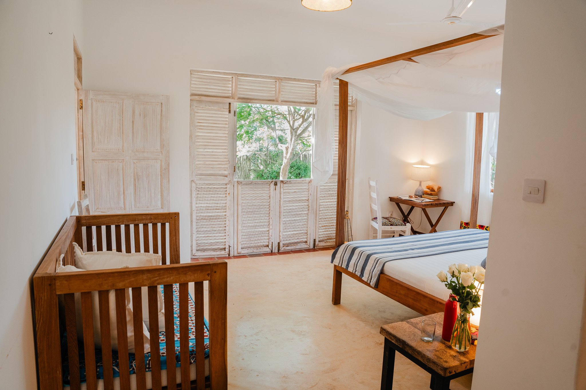 Downstairs bedroom featuring x2 king size beds, a baby cot, closet and en-suite bathroom, with doors opening to the front garden.
