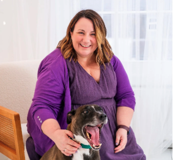 Lady in purple sitting with her dog smiling at the camera