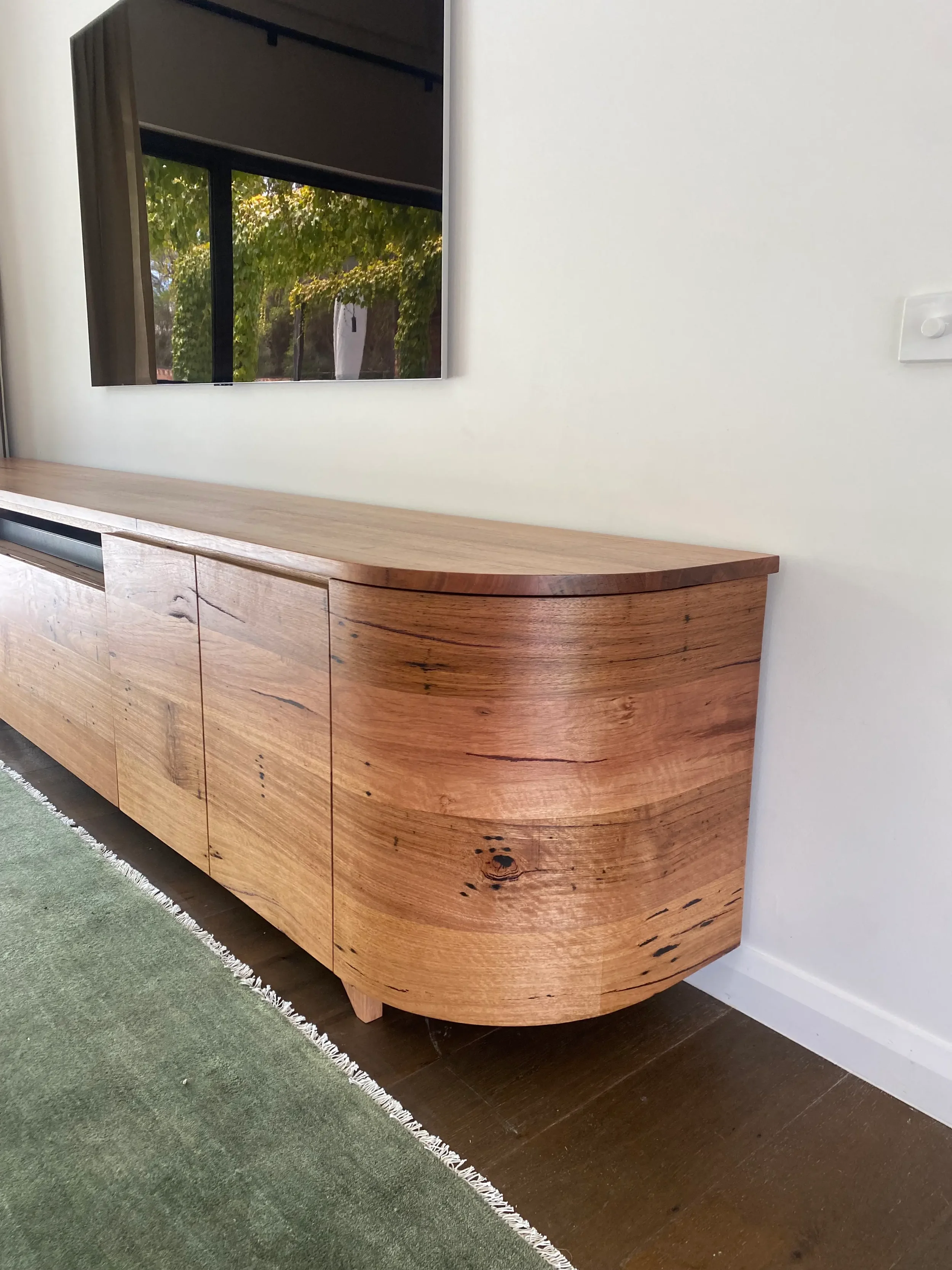 Solid messmate timber entertainment unit with curved doors and continuing grain. Featured at our clients home in Bellbrae. Hand made on the Surf Coast by Georgie Wood
