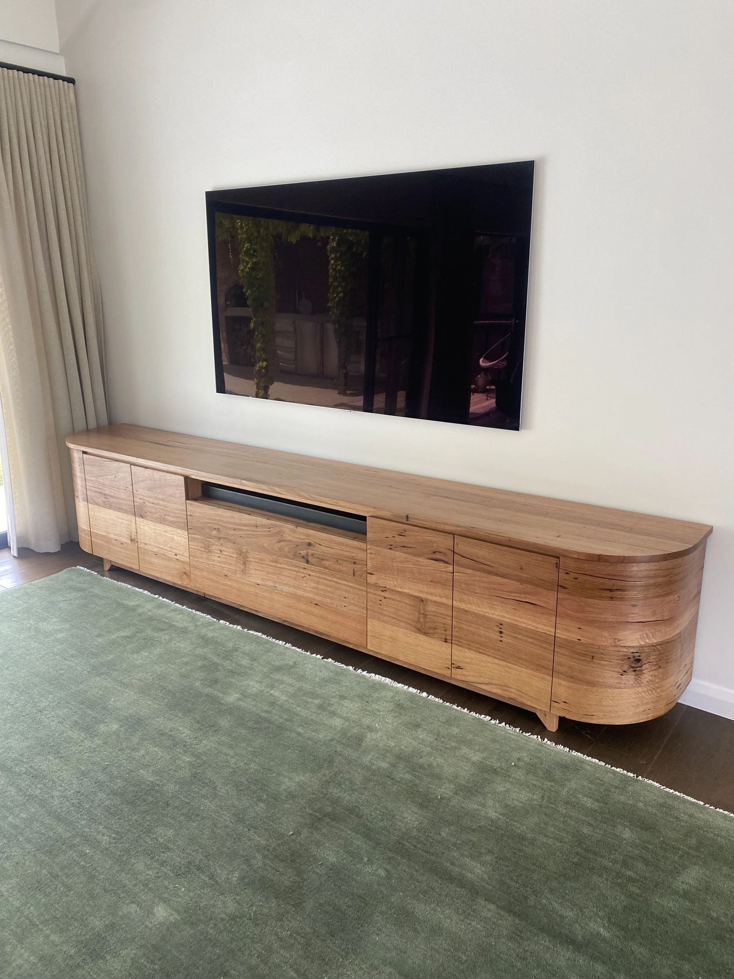 Front on view of the solid messmate timber entertainment unit with curved doors and continuing grain. Featured at our clients home in Bellbrae. Hand made on the Surf Coast by Georgie Wood
