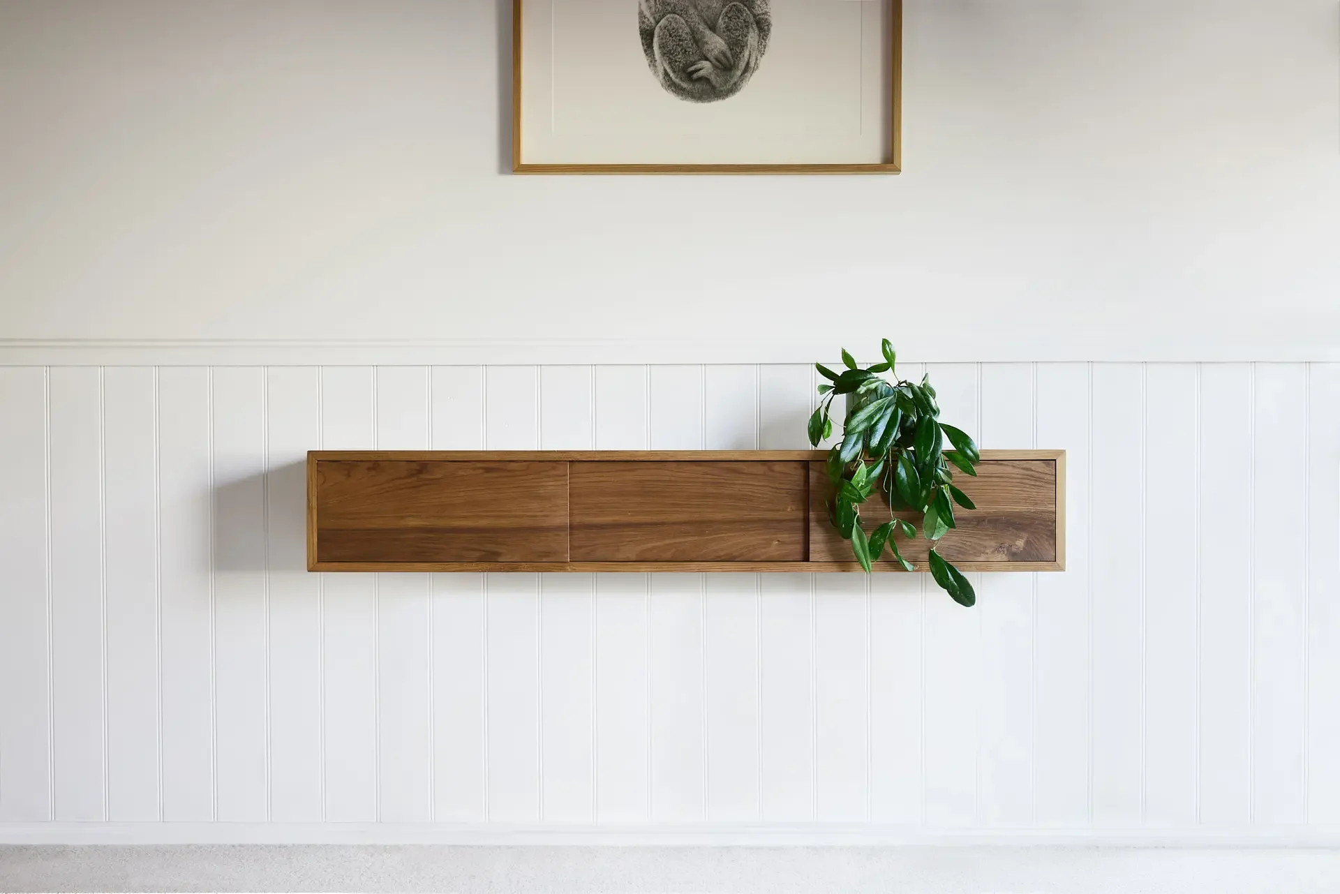 Floating blackwood storage unit, attached to a white wall under a Koala sketch artwork