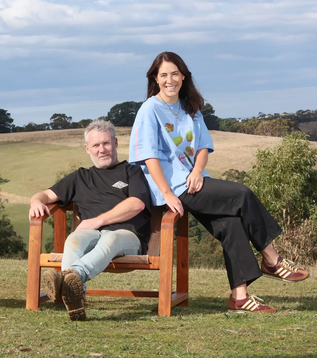 Anthony Christie & Kirsty Lake sitting on their Wrangler Chair in the rolling hills of Ashmore Arts in Torquay