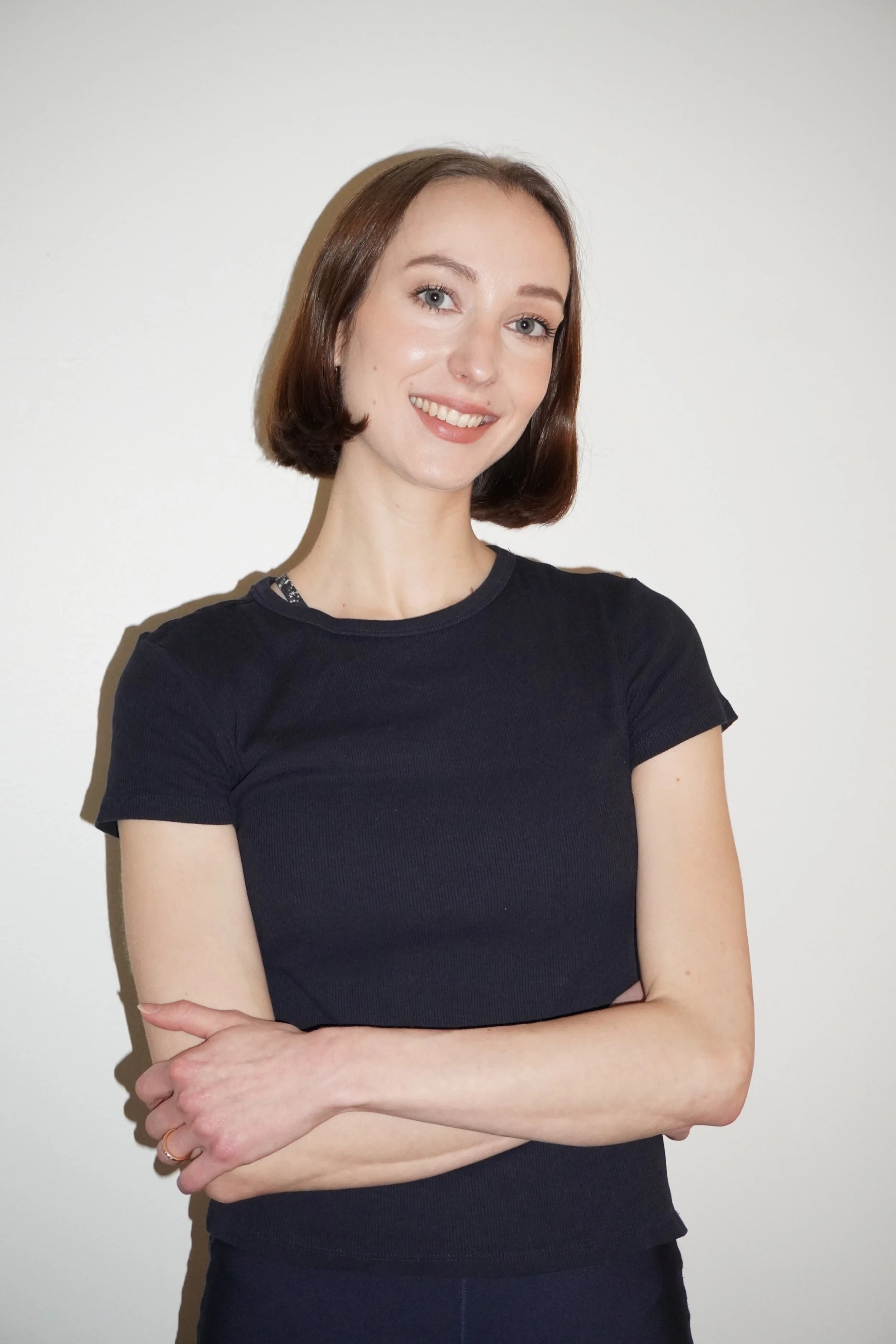 A woman with short brown hair standing and smiling.