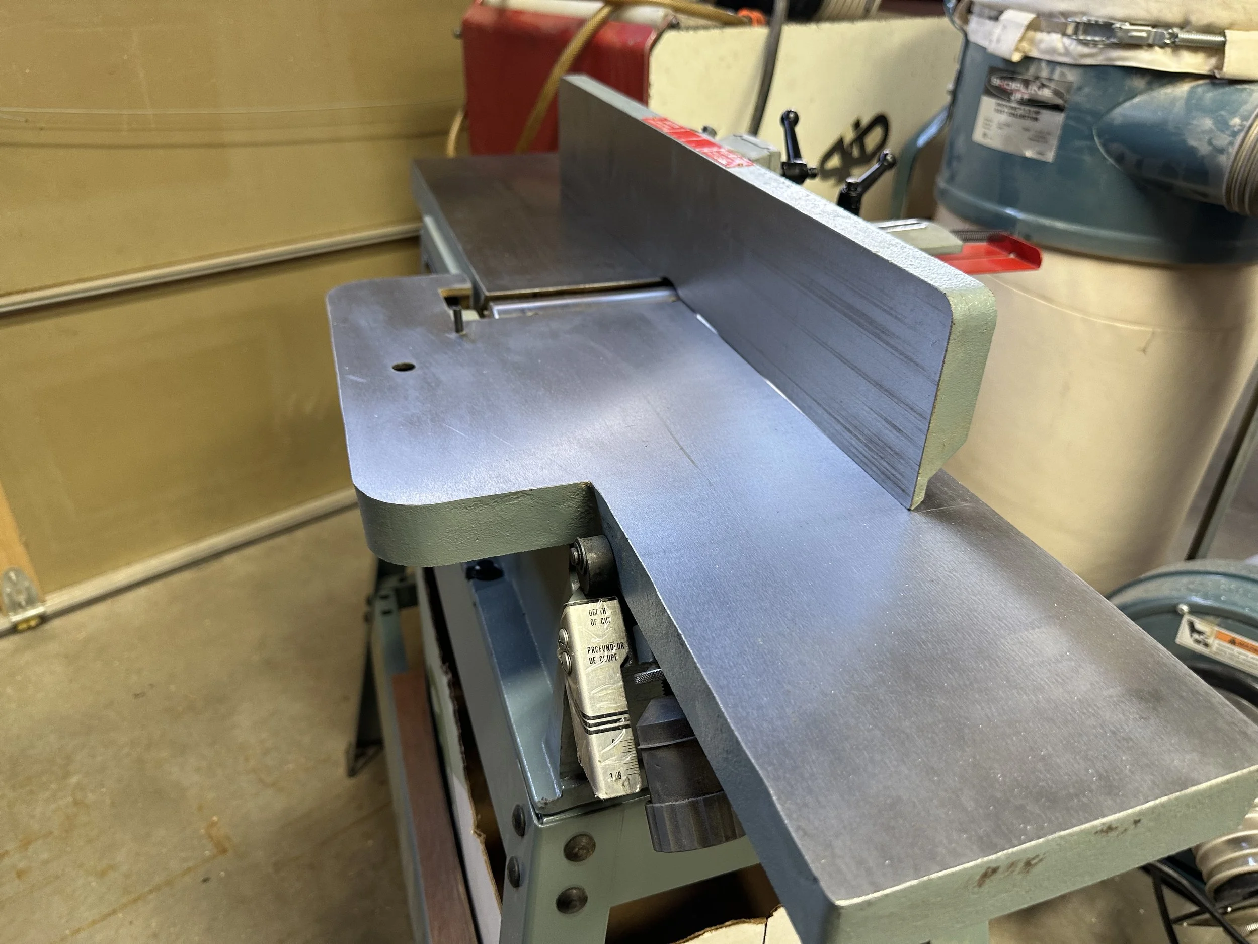 A metal table saw in a workshop with a baltic birch plywood board positioned on the saw table for cutting.