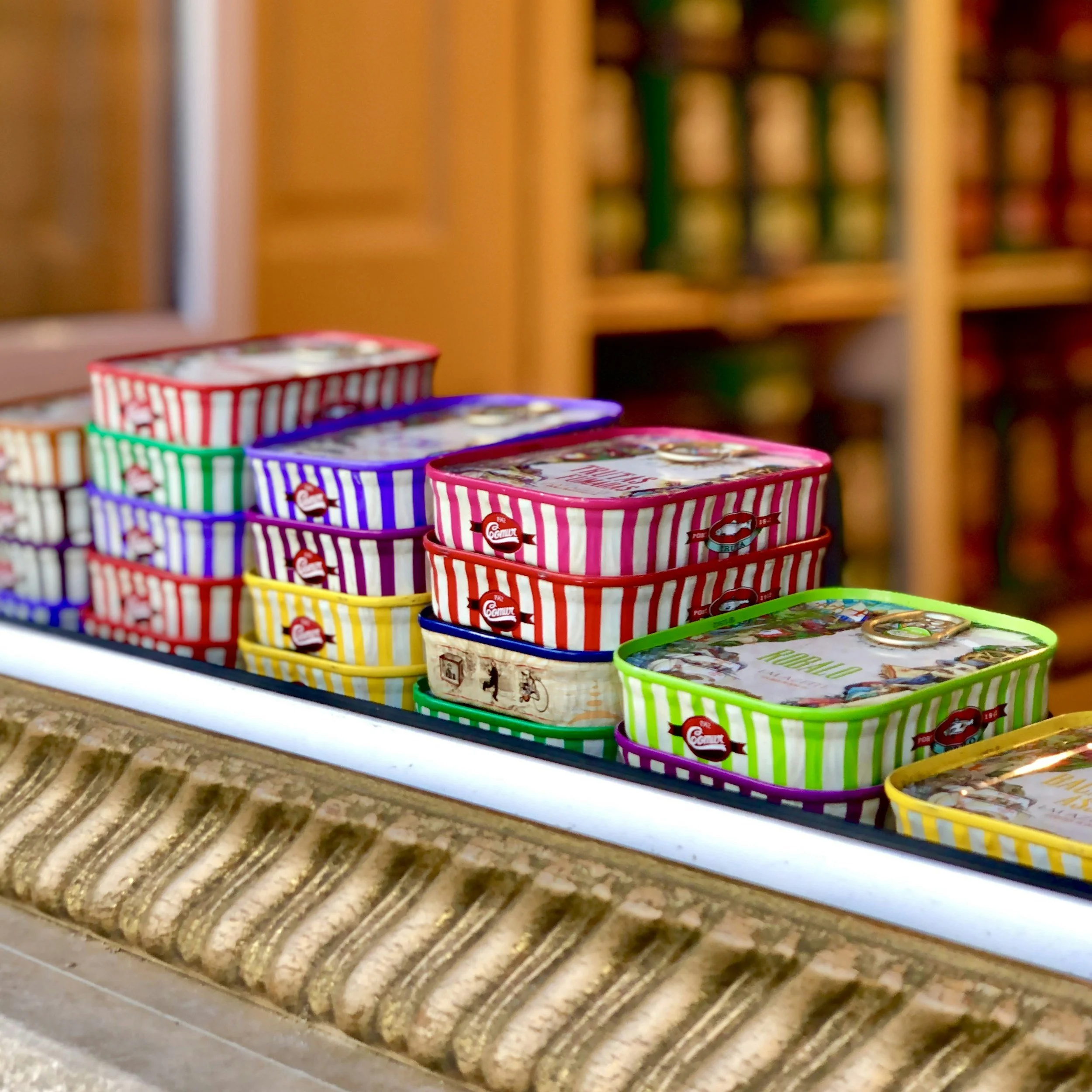 Stacked colorful tins with striped patterns on a display counter in a store.