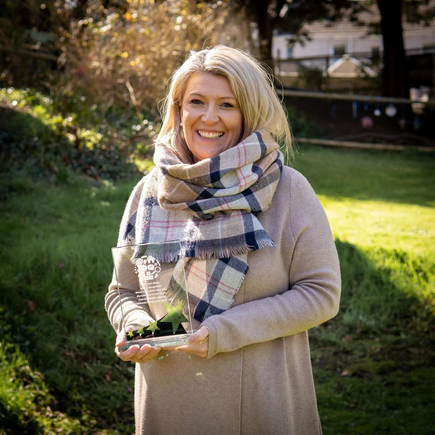 A young woman with long, blonde hair and blue eyes smiling at the camera, wearing a white and black striped shirt, standing in front of a colorful graffiti wall.