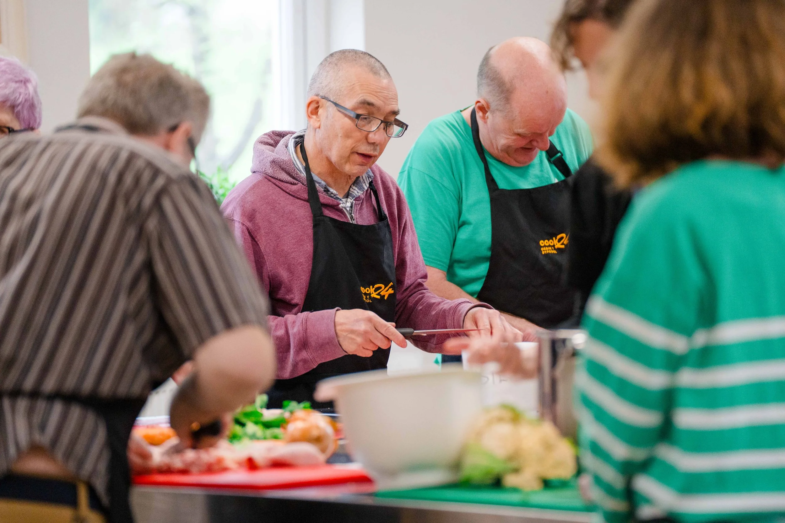 People wearing aprons cooking together in a kitchen.