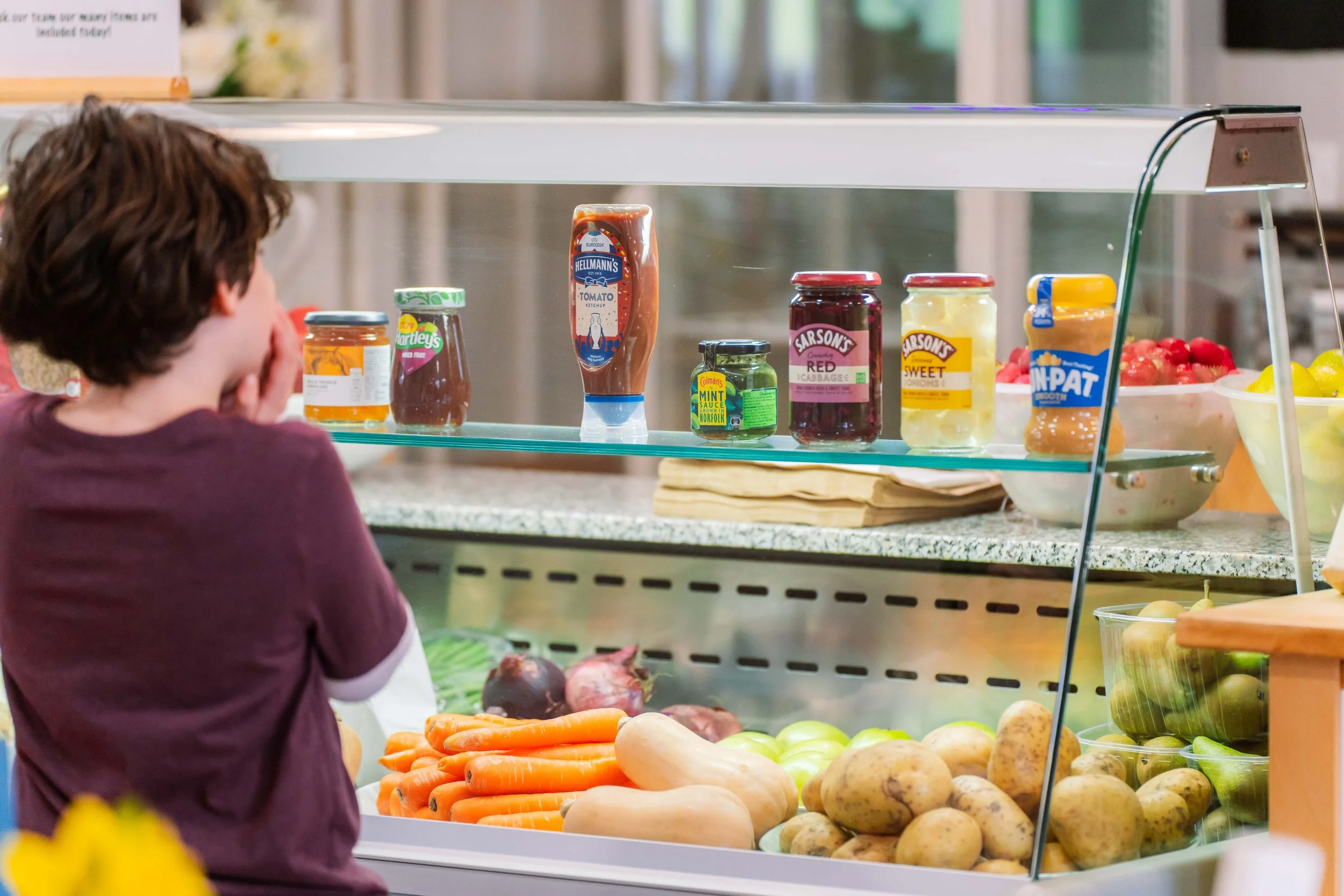 Person looking at a display of fresh vegetables and condiments at a grocery store