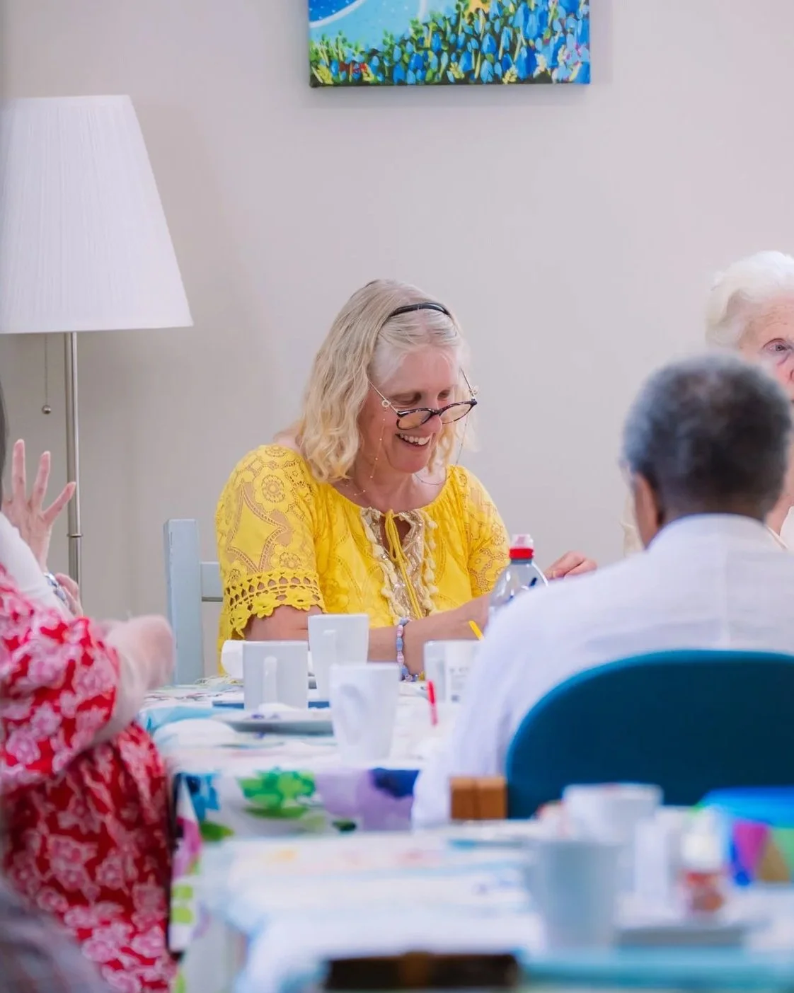 A group of elderly people sitting around a dining table, smiling and engaging in conversation at a social gathering.