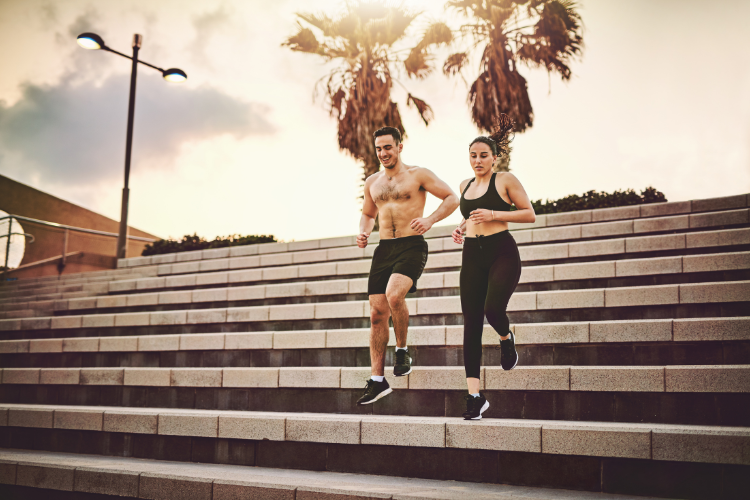 Man and woman running up outdoor stairs at sunset