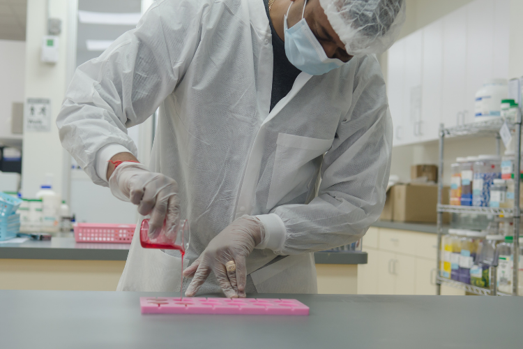 Pharmacist in protective gear preparing a compounded medication