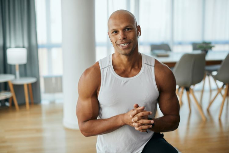 Fit, smiling man in a tank top at home
