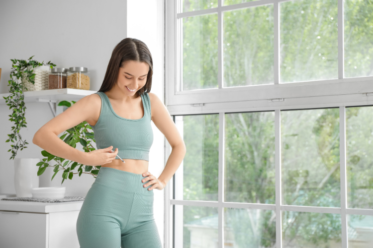 Woman in workout clothes using an injection pen at her waist
