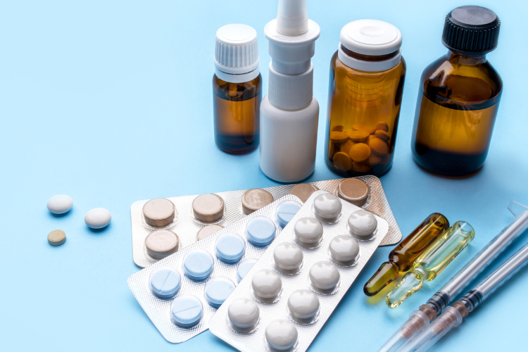 Assorted prescription bottles, vials and blister packs on a blue background