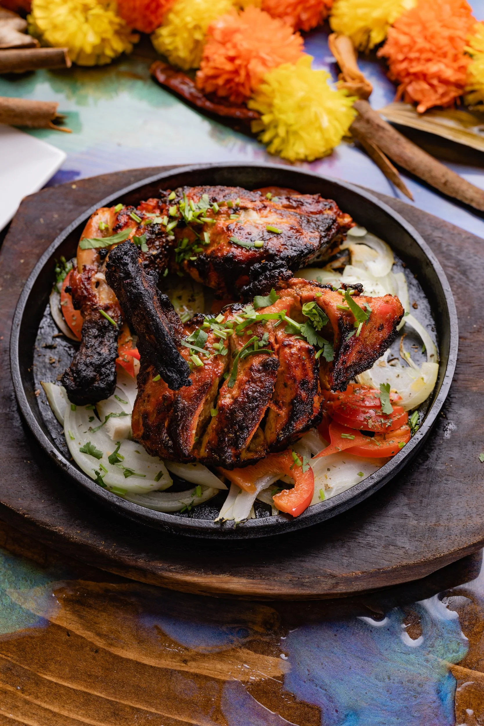 Grilled chicken with charred ribs and fresh vegetables on a cast iron skillet, garnished with chopped herbs