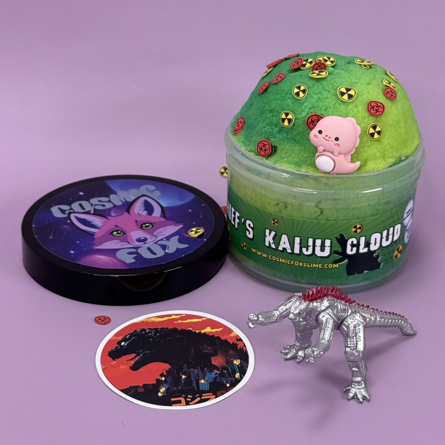 Chief's Kaiju Cloud: A two-tone green swirl cloud slime with themed charms sprinkled on top. Sat next to it's lid, a kaiju toy,  and a kaiju sticker.