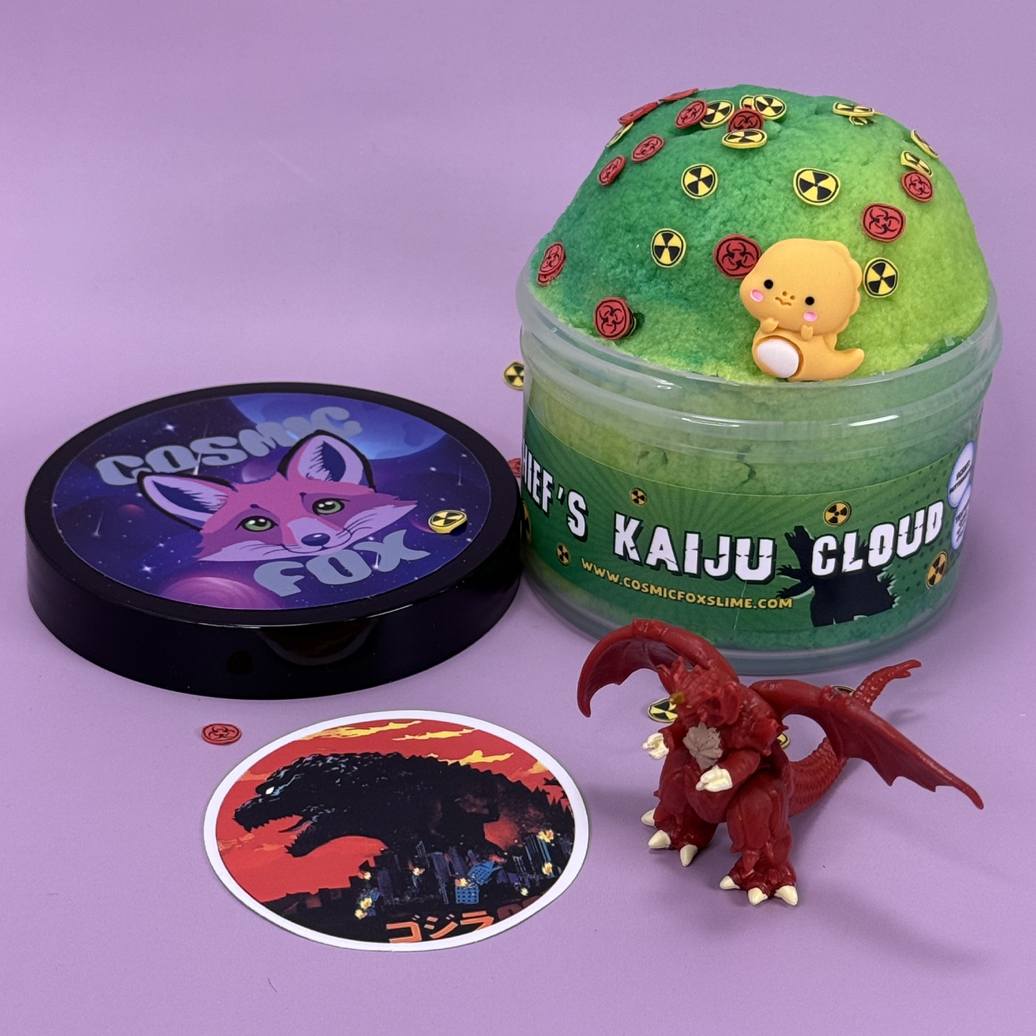 Chief's Kaiju Cloud: A two-tone green swirl cloud slime with themed charms sprinkled on top. Sat next to it's lid, a kaiju toy,  and a kaiju sticker.
