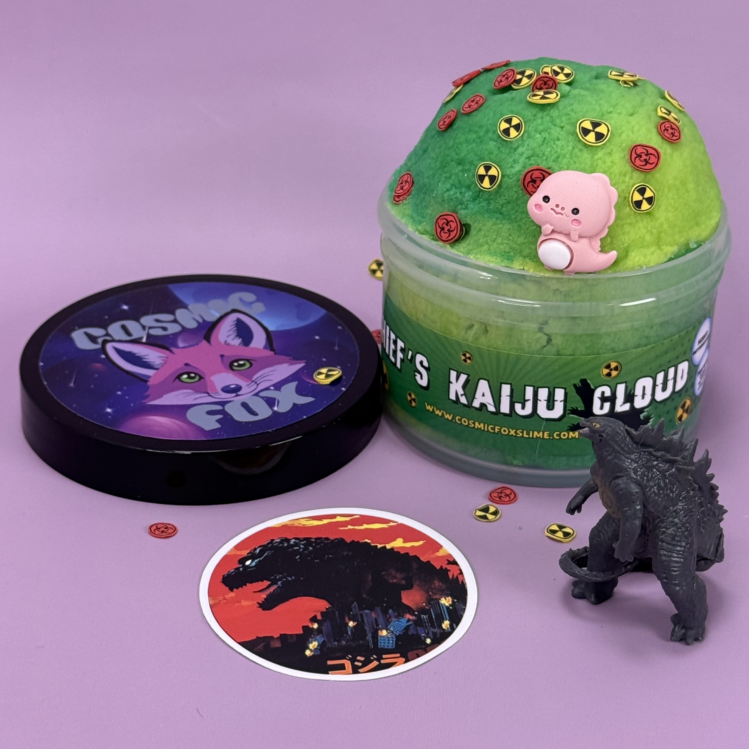 Chief's Kaiju Cloud: A two-tone green swirl cloud slime with themed charms sprinkled on top. Sat next to it's lid, a kaiju toy,  and a kaiju sticker.