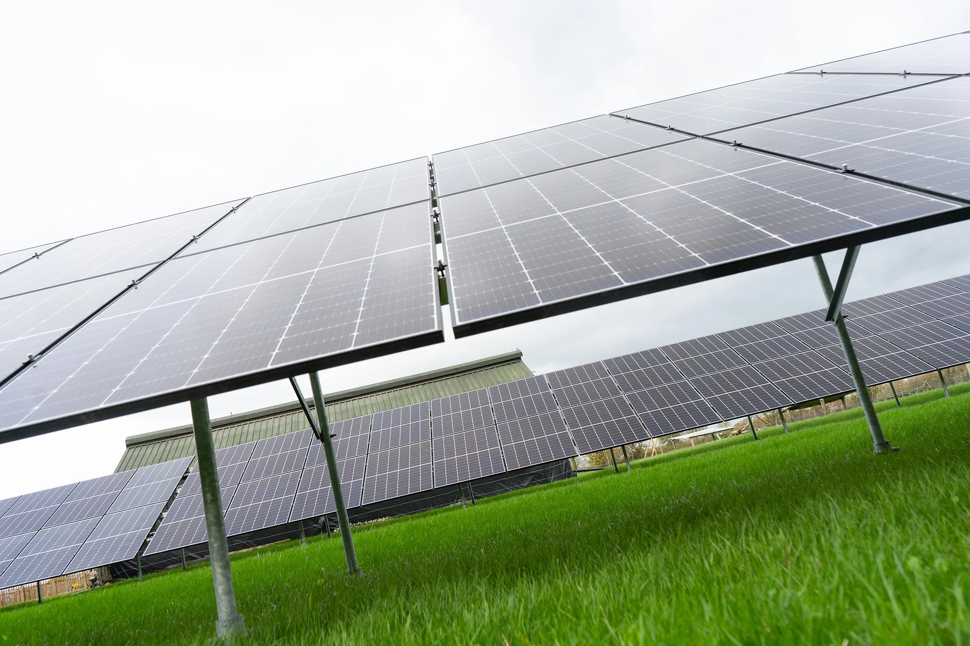 Solar panels on grass field under cloudy sky