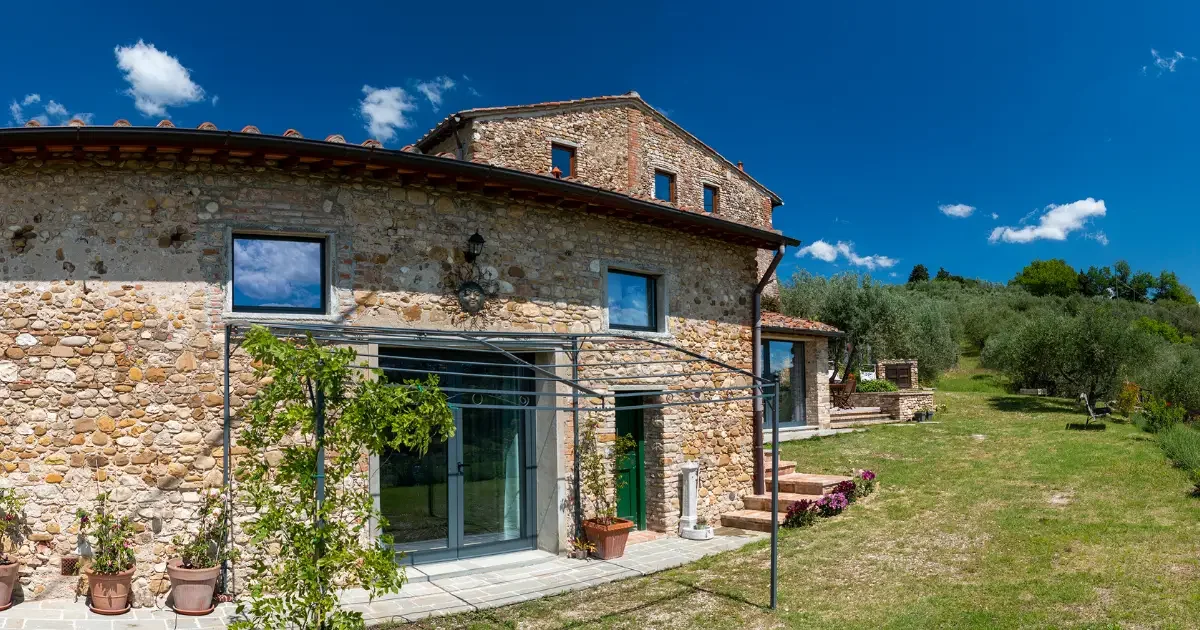 Seeds: One day Retreat alla Sorripa: casa in stile rustico con muri di pietra, grandi finestre e un giardino verde, sotto un cielo blu con nuvole.