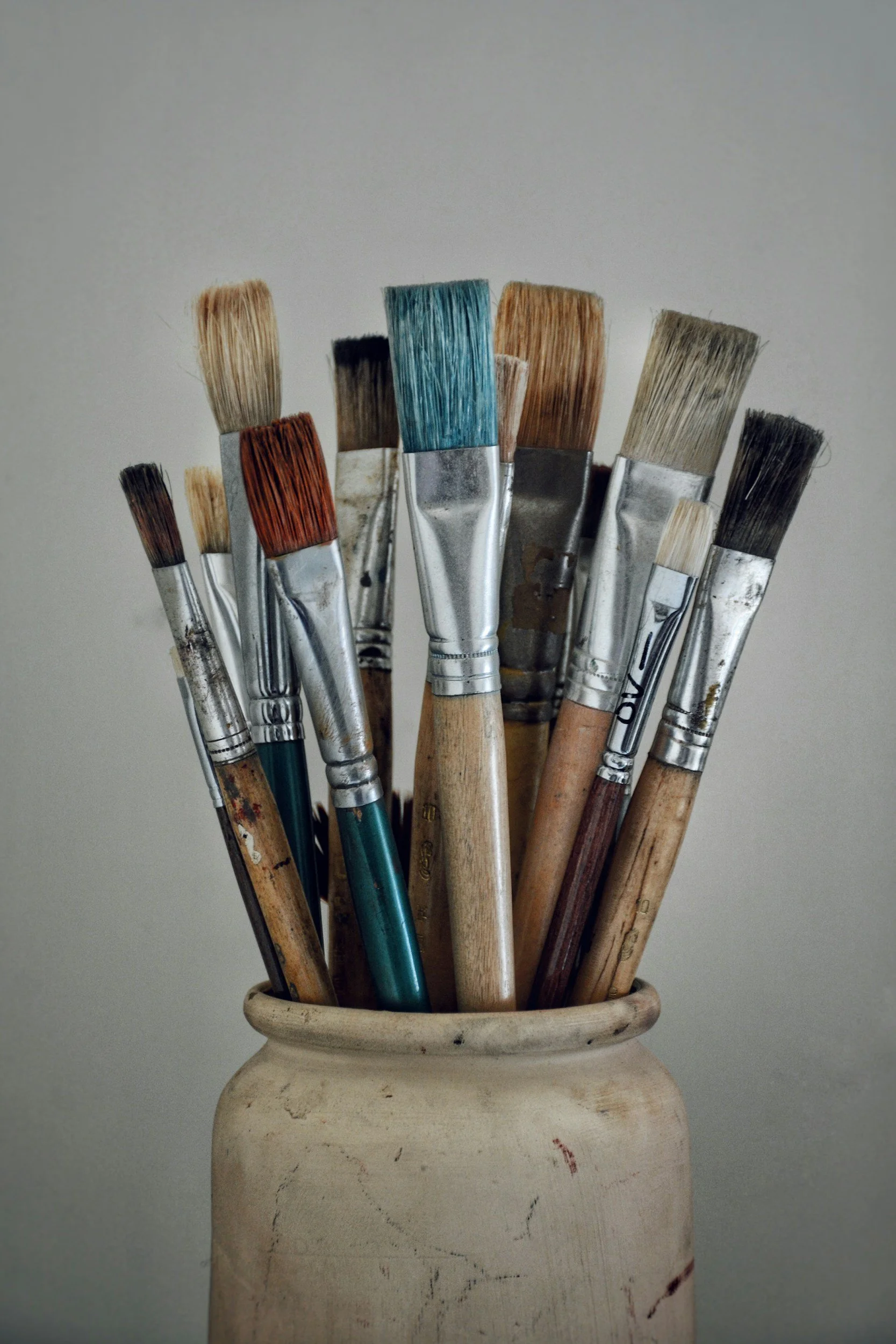 A container holding several used paintbrushes.