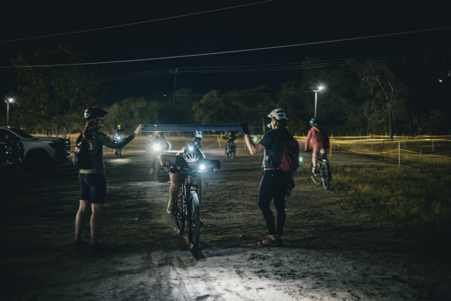 Femmes riders on a trail at dusk with their bike lights on